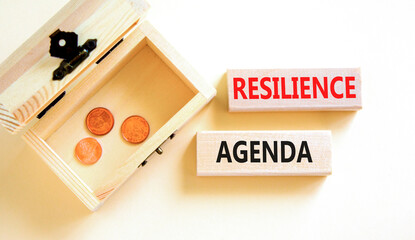Resilience agenda symbol. Concept word Resilience agenda typed on wooden blocks. Beautiful white table white background. Wooden chest with coins. Business and resilience agenda concept. Copy space.