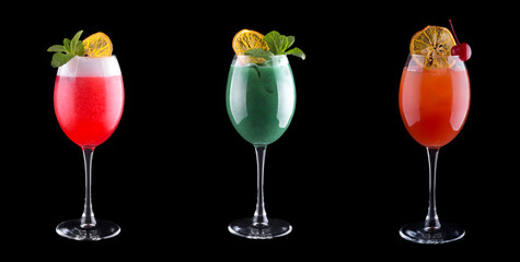 Alcoholic cocktails of different colors in cocktail glasses with mint, cherry and ice. Isolated on black