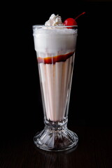Milk shake with cream and cocktail cherry. Isolated on black