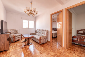 Living room with doors to other rooms and checkerboard parquet floor and three-seater sofa upholstered in fabric with wooden details