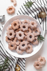 Sweet shortbresd cookies on a plate with Christmas decoration on a white background. Flower shaped butter cookies.