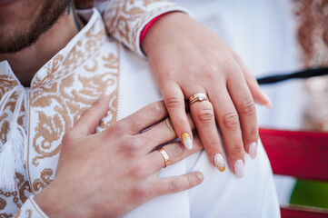 Wedding rings on the hands of the newlyweds. Golden rings on the hands of a guy and a girl