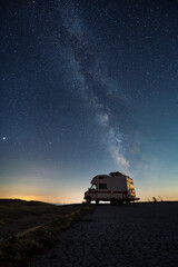 Amazing view of a camper van on the background of a starry night sky with Milky Way galaxy - 552391105
