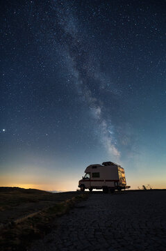 Amazing view of a camper van on the background of a starry night sky with Milky Way galaxy