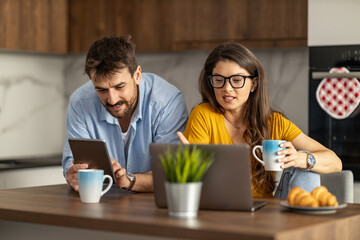 Couple in modern kitchen,using laptop