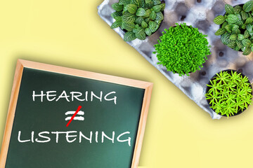 Hearing not equal listening written on chalkboard  with planting a few trees. Communication with...