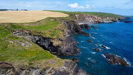Farm fields on the rocky shore of the Celtic Sea, south of Ireland, County Cork. Beautiful coastal area. Turquoise waters of the Atlantic. Picturesque stone hills. Drone photo. View from above.