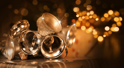 	Gold and silver christmas bells and heart  fairy lights in front of christmas tree.