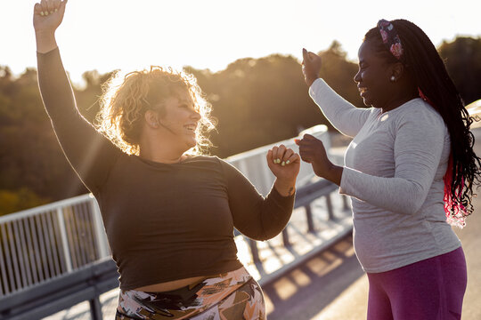 Two excited young plus size women jogging together.
