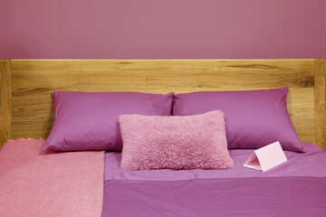 Scandinavian bedroom interior with wooden bed and cozy pillows in violet color