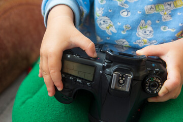 Toddler's hands hold a camera and press buttons close-up