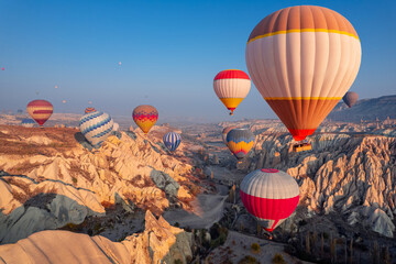 Obraz premium Aerial view amazing sunrise landscape in Cappadocia with colorful hot air balloon fly in sky over deep canyons, valleys. Concept banner travel Turkey