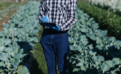 Futuristic businessman farms vegetables and crops using modern AI technology using mobile phones, temperature and humidity sensors, water tracking, climate control, holographic data data icons.