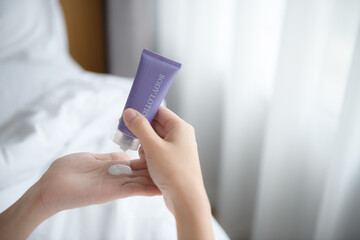 Close up of women applying body lotion cream on hand.