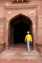 Indian man dressed in yellow shirt entering a temple in India