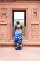 Fototapeta na wymiar Indian woman is looking through a window in a temple. Agra, Uttar Pradesh (India).