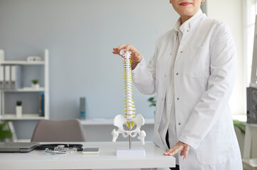 Female doctor with anatomical spine model. Cropped shot of orthopedic surgeon in white lab coat...