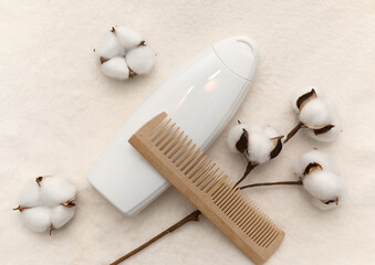 White plastic container with white cotton flowers and wooden comb.