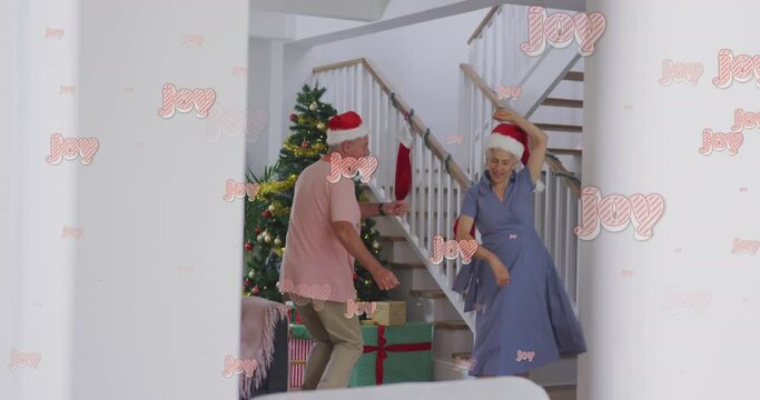 Animation of joy text over senior caucasian couple wearing santa hats and dancing