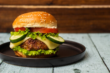 Burger in bun with beef meat and cheese, served on black plate