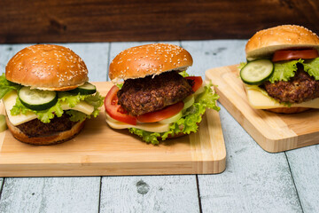 Burgers with beef meat, cheese and lettuce, served on cutting board