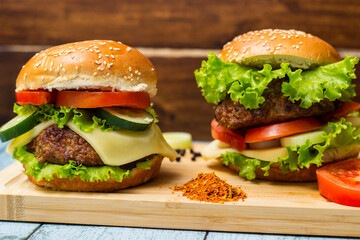 Burgers with beef meat, cheese and lettuce, served on cutting board