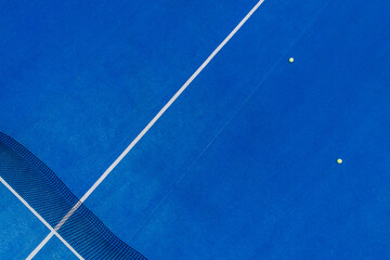 aerial drone view of a blue paddle tennis court with balls on its surface