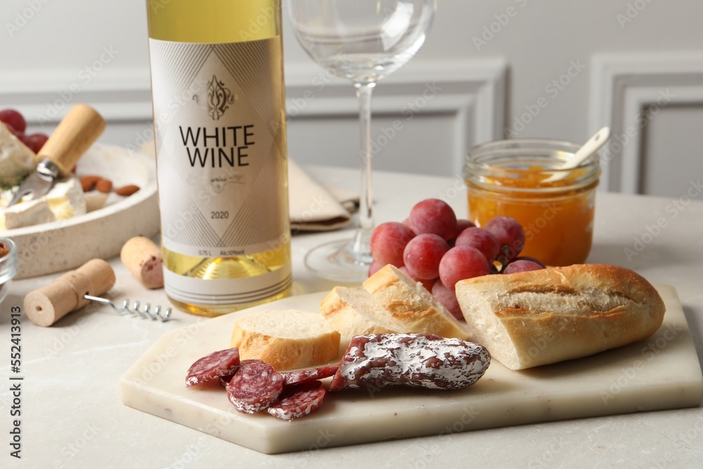 Sticker Bottle of white wine, glass and snacks on table, closeup