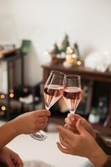 Drinking sparkling rose wine or champagne at home decorated for winter holidays. Christmas season festive drinks.