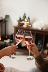 Drinking sparkling rose wine or champagne at home decorated for winter holidays. Christmas season festive drinks.