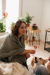 woman with corgi dog at home. Beautiful young caucasian woman with brown hair at cozy home apartment. Casual portrait of a woman with a drink on a couch.