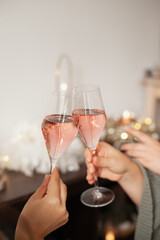 Holding two glasses of rose sparkling wine to cheers for Christmas or New year. Celebrating at party. Happy Birthday or anniversary. Festive drinks background