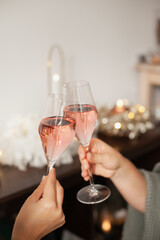 Holding two glasses of rose sparkling wine to cheers for Christmas or New year. Celebrating at party. Happy Birthday or anniversary. Festive drinks background