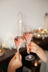 Holding two glasses of rose sparkling wine to cheers for Christmas or New year. Celebrating at party. Happy Birthday or anniversary. Festive drinks background