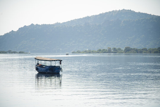 Abandoned Boat Adrift Marooned In The Middle Of Water Of Lake Pichola Surrounded By Aravalli Hills In Tourist City Of Udaipur Rajasthan