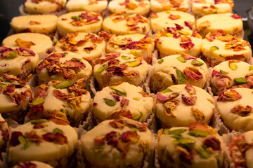 Delicious sweet snacks with nuts on tops arranged in racks in sweet shop