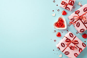 Saint Valentine's Day concept. Top view photo of present boxes in wrapping paper with kiss lips pattern heart shaped saucer candies and confetti on isolated pastel blue background with copyspace