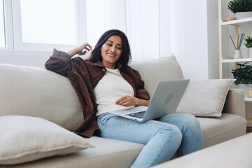 Obraz premium Woman freelancer on day off sitting on sofa with laptop at home online video chat call, smile