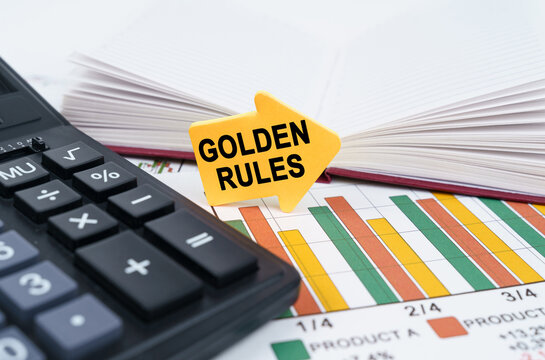 On the business charts there is a notepad, a pen and an arrow sticker with the inscription - Golden Rules