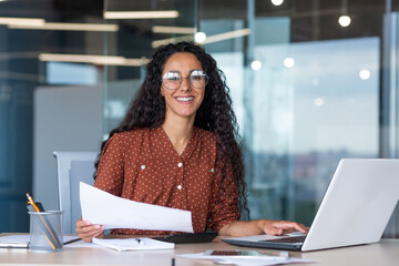 Portrait of a young Latin American woman designer, architect, freelancer. He sits in the office at...