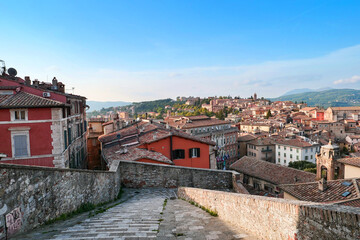 Down the street. A panoramic view of the city opens up; you can see the roofs of houses and...