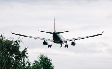 Passenger plane comes in for landing in cloudy weather.