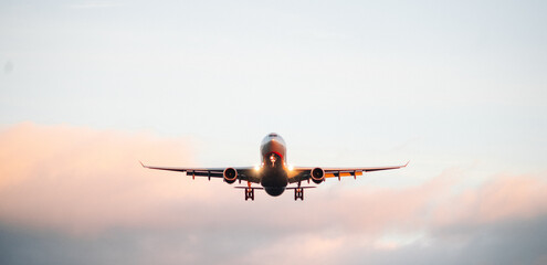 The silhouette of a passenger plane coming in for landing against the backdrop of the sunset sky.