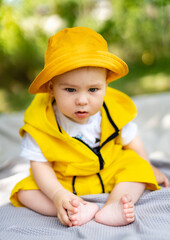 Little baby boy sitting up on a blanket in the park. Outdoor fun for children.