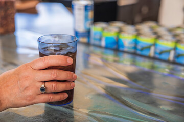 Close up view of woman's hand holding plastic cup with ice soda.