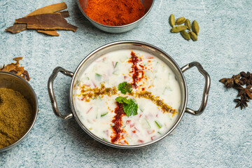 Chatpati Mixed Raita with cucumber, onion, masala and dahi or yogurt served in a dish isolated on grey background top view of bangladesh food