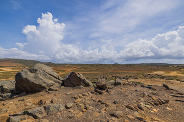 Beautiful view of large stones on background of desert on blue sky with background of white clouds. Aruba.