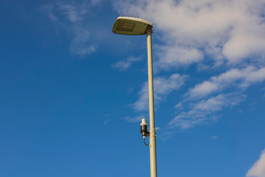 Technology view of light sensor on street lighting pole on blue sky with rare white clouds background. Sweden. 