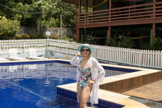 Woman Wearing A One Piece Swimsuit And A Cover Up Hanging Out By The Pool