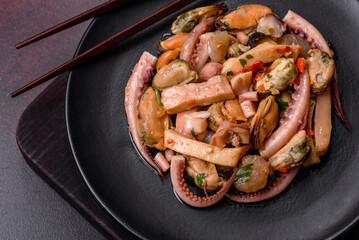 Delicious pickled seafood salad or cocktail on a black plate